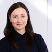 Eine junge Frau mit langen braunen Haaren lächelt in die Kamera.