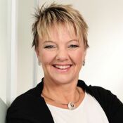 Eine Frau mit kurzen blonden Haaren lacht freundlich.