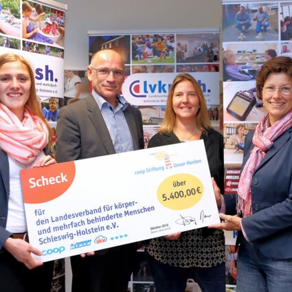 Ein Mann und drei Frauen halten einen Spendenscheck der Unser Norden Stiftung in den Händen