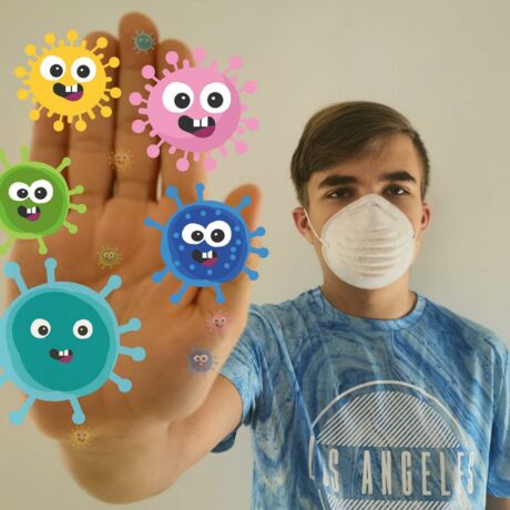 Ein Junge mit FFP2-Maske hält seine Handfläche hoch, auf der Grafiken von bunten Viren abgebildet sind