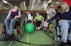 Eine kleine Gruppe junger Menschen spielt mit einem grünen Pezziball