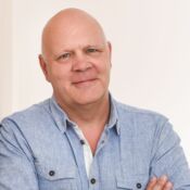 Ein Mann mit Glatze lächelt in die Kamera