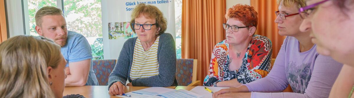 Ein Mann und fünf Frauen sitzen an einem Tisch und tauschen sich aus